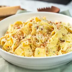 En skål med krämig pasta limone, toppad med pinjenötter och riven parmesan. Perfekt för en snabb och smakrik middag.