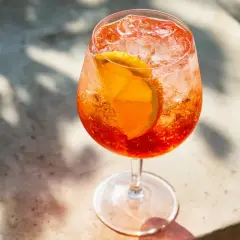 Ett glas med en bubblig Aperol Spritz, fylld med is och en apelsinskiva. Perfekt för en solig dag.