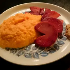 En portion rotmos utan potatis, med skivade röda äpplen och en klick senap.