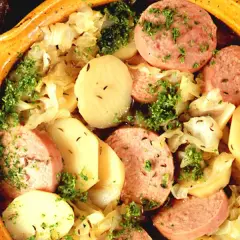 En värmande korvgryta med potatis, kål och persilja i en rustik keramikskål.