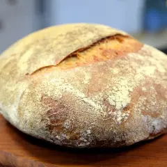 En vackert bakad surdegslimpa, perfekt för ditt surdegslimpa recept. Den gyllene skorpan och mjöliga ytan inbjuder till en smakrik upplevelse.