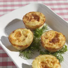 Små, gyllene potatis i muffinsform, dekorerade med färska örter. Perfekt som tillbehör eller en lätt måltid.