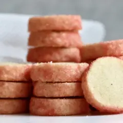 Små, runda kex med rosa socker runt kanterna, staplade på varandra. Perfekt för ett enkelt brysselkex recept.