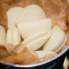En skål med ångade bao buns, inlindade i bakplåtspapper. De är mjuka, vita och redo att fyllas med goda saker.