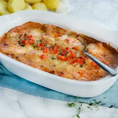 Gratinerad kycklinglårfile i ugnsform, toppad med tomat och örter. Ett härligt kycklinglårfile recept för middagen.