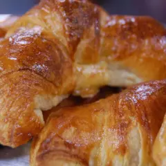 Nybakade, gyllene croissanter som ser ut att vara perfekt att baka.