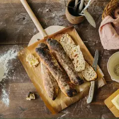 Nybakade surdegsbaguetter på en bakspade, med mjöl och smör redo för ett gott surdeg recept.