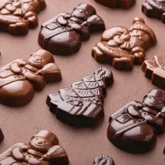 Chokladfigurer av tomtar och snögubbar, perfekt tempererad vit choklad för julens godsaker.
