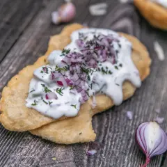 En friterad langos med gräddfil, hackad rödlök och dill. Perfekt för ett snabbt langos recept.