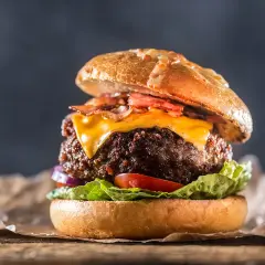 En saftig hamburgare med ost och bacon, perfekt för att grilla hamburgare en solig dag.