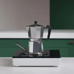 En mokkakanne står på en induktionshäll, redo att brygga kaffe.
