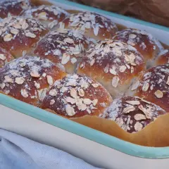 Nybakade frallor med havregryn och pudrat mjöl i en ugnsform. Perfekta för frukost eller fika.