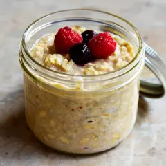 Overnight oats med proteinpulver i burk, toppad med hallon och blåbär. Perfekt för en snabb och näringsrik frukost.