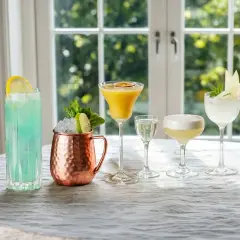 Fem olika drinkar, inklusive en blå, en gul med passionsfrukt och en vit med äpple, står uppradade. Perfekt för att njuta av goda vodka drinkar.