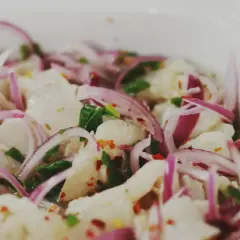 En närbild på en skål med färsk ceviche, med bitar av vit fisk, rödlök, chili och örter. Perfekt för ett somrigt ceviche recept.