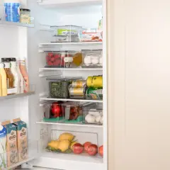 Ordning och reda i kylen! Här ser vi en genomtänkt placering av mat i kylskåp med frukt, grönsaker, drycker och mejeriprodukter i genomskinliga behållare.