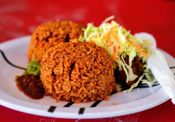 Två portioner jollof rice med sallad och en kryddig sås. En smakrik rätt som lockar.