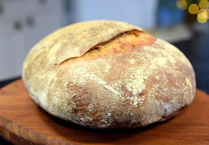 En vackert bakad surdegslimpa, perfekt för ditt surdegslimpa recept. Den gyllene skorpan och mjöliga ytan inbjuder till en smakrik upplevelse.