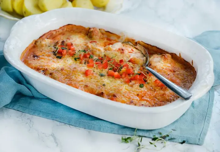Gratinerad kycklinglårfile i ugnsform, toppad med tomat och örter. Ett härligt kycklinglårfile recept för middagen.