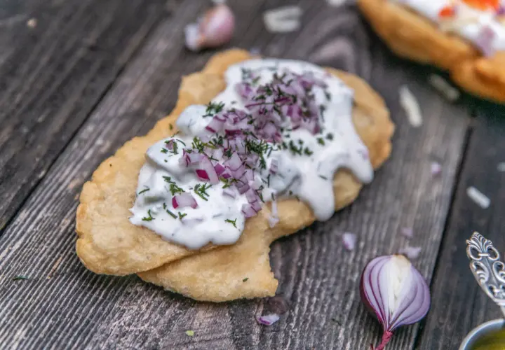 En friterad langos med gräddfil, hackad rödlök och dill. Perfekt för ett snabbt langos recept.