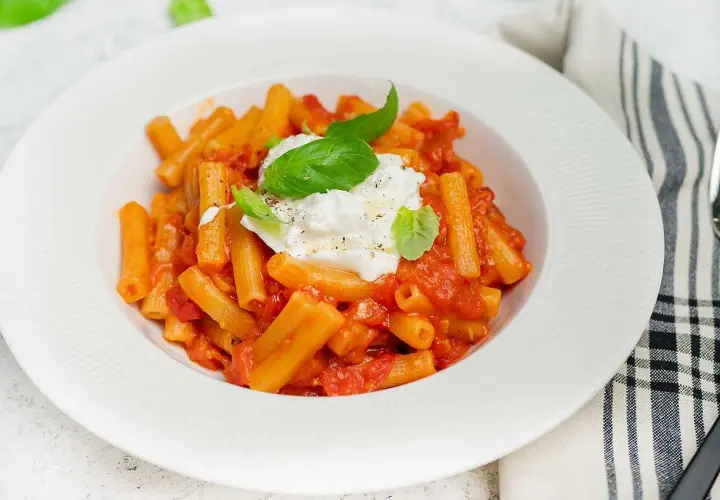 En krämig pasta med tomatsås och en generös klick burrata, perfekt för ett enkelt burrata recept. Garnerad med färsk basilika.