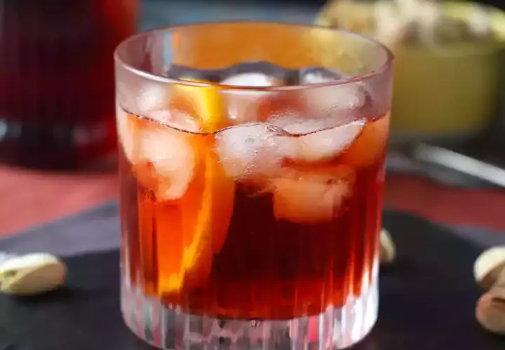Ett glas Negroni med is och apelsinskiva, perfekt för att följa ett negroni recept.