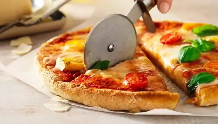 En pizza med tomater och basilika skärs upp. Ett perfekt glutenfri pizzadeg recept för alla.
