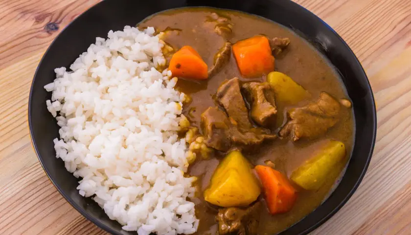 En tallrik med ångande ris och en mustig japansk curry med mört kött, potatis och morötter.