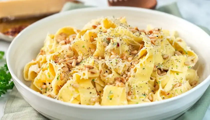 En skål med krämig pasta limone, toppad med pinjenötter och riven parmesan. Perfekt för en snabb och smakrik middag.