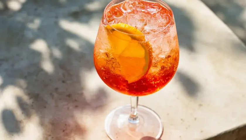 Ett glas med en bubblig Aperol Spritz, fylld med is och en apelsinskiva. Perfekt för en solig dag.