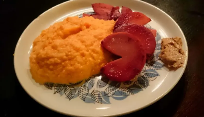En portion rotmos utan potatis, med skivade röda äpplen och en klick senap.