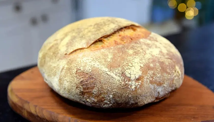 En vackert bakad surdegslimpa, perfekt för ditt surdegslimpa recept. Den gyllene skorpan och mjöliga ytan inbjuder till en smakrik upplevelse.
