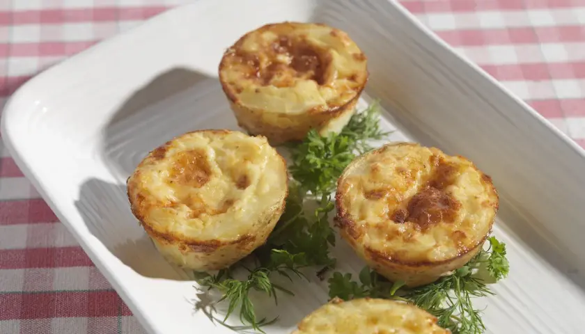 Små, gyllene potatis i muffinsform, dekorerade med färska örter. Perfekt som tillbehör eller en lätt måltid.