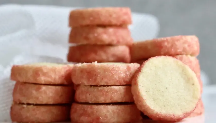 Små, runda kex med rosa socker runt kanterna, staplade på varandra. Perfekt för ett enkelt brysselkex recept.