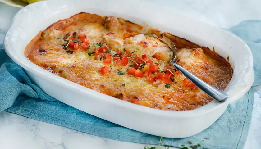 Gratinerad kycklinglårfile i ugnsform, toppad med tomat och örter. Ett härligt kycklinglårfile recept för middagen.