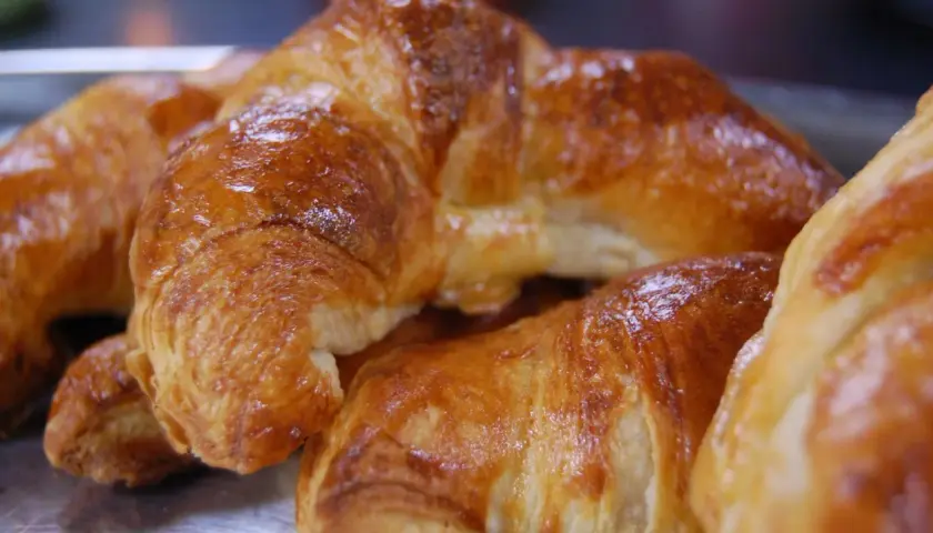 Nybakade, gyllene croissanter som ser ut att vara perfekt att baka.