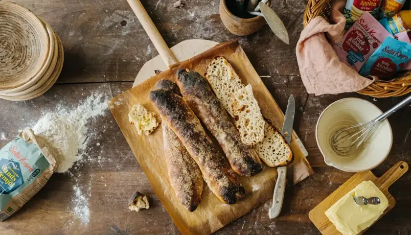 Nybakade surdegsbaguetter på en bakspade, med mjöl och smör redo för ett gott surdeg recept.