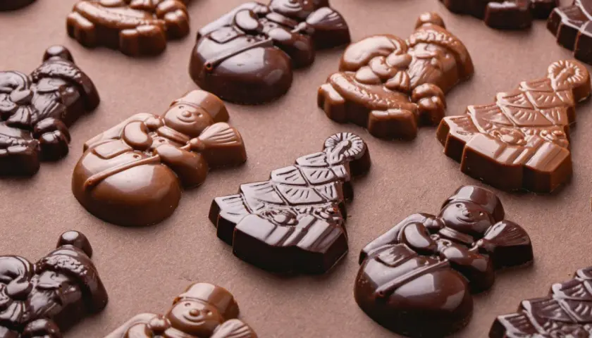 Chokladfigurer av tomtar och snögubbar, perfekt tempererad vit choklad för julens godsaker.