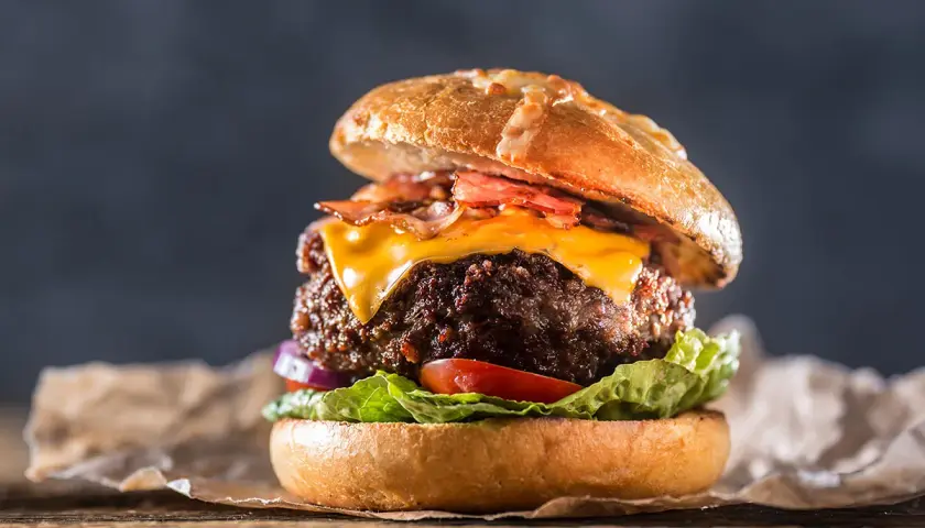 En saftig hamburgare med ost och bacon, perfekt för att grilla hamburgare en solig dag.