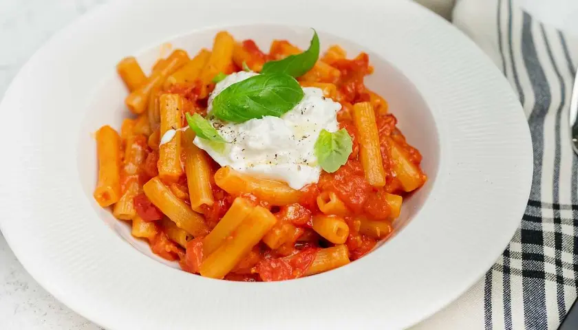 En krämig pasta med tomatsås och en generös klick burrata, perfekt för ett enkelt burrata recept. Garnerad med färsk basilika.