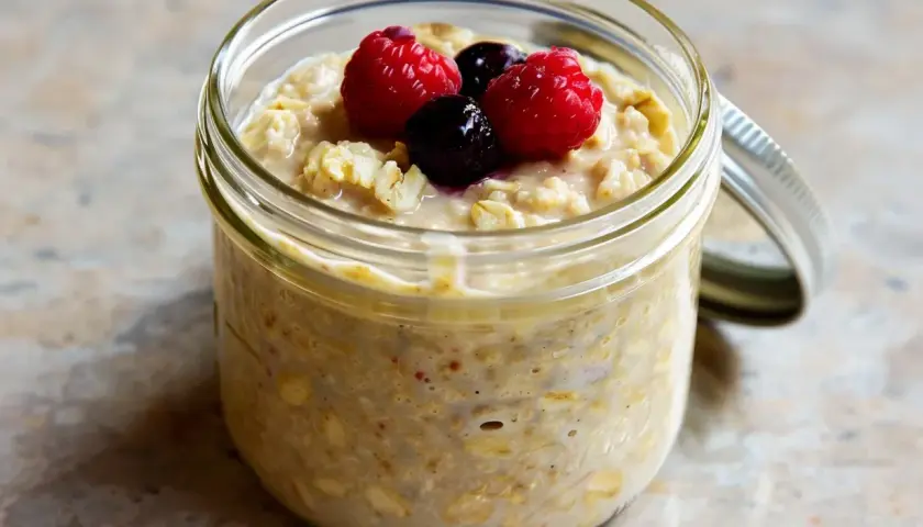 Overnight oats med proteinpulver i burk, toppad med hallon och blåbär. Perfekt för en snabb och näringsrik frukost.