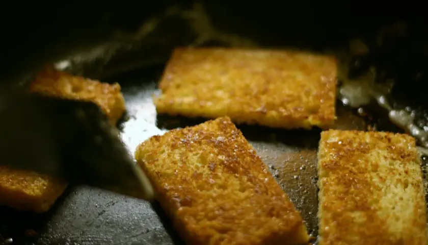 Gyldene skiver av brioche steker i en varm stekepanne. Snart redo att baka brioche!