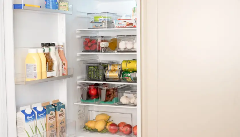 Ordning och reda i kylen! Här ser vi en genomtänkt placering av mat i kylskåp med frukt, grönsaker, drycker och mejeriprodukter i genomskinliga behållare.