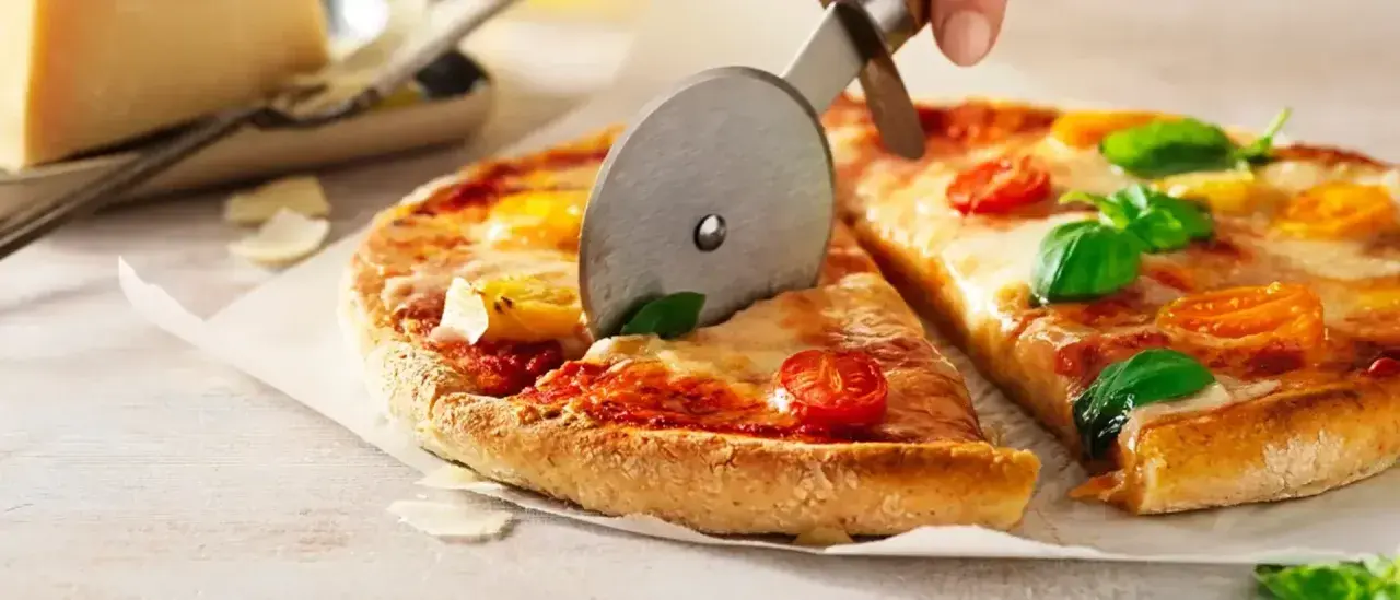En pizza med tomater och basilika skärs upp. Ett perfekt glutenfri pizzadeg recept för alla.