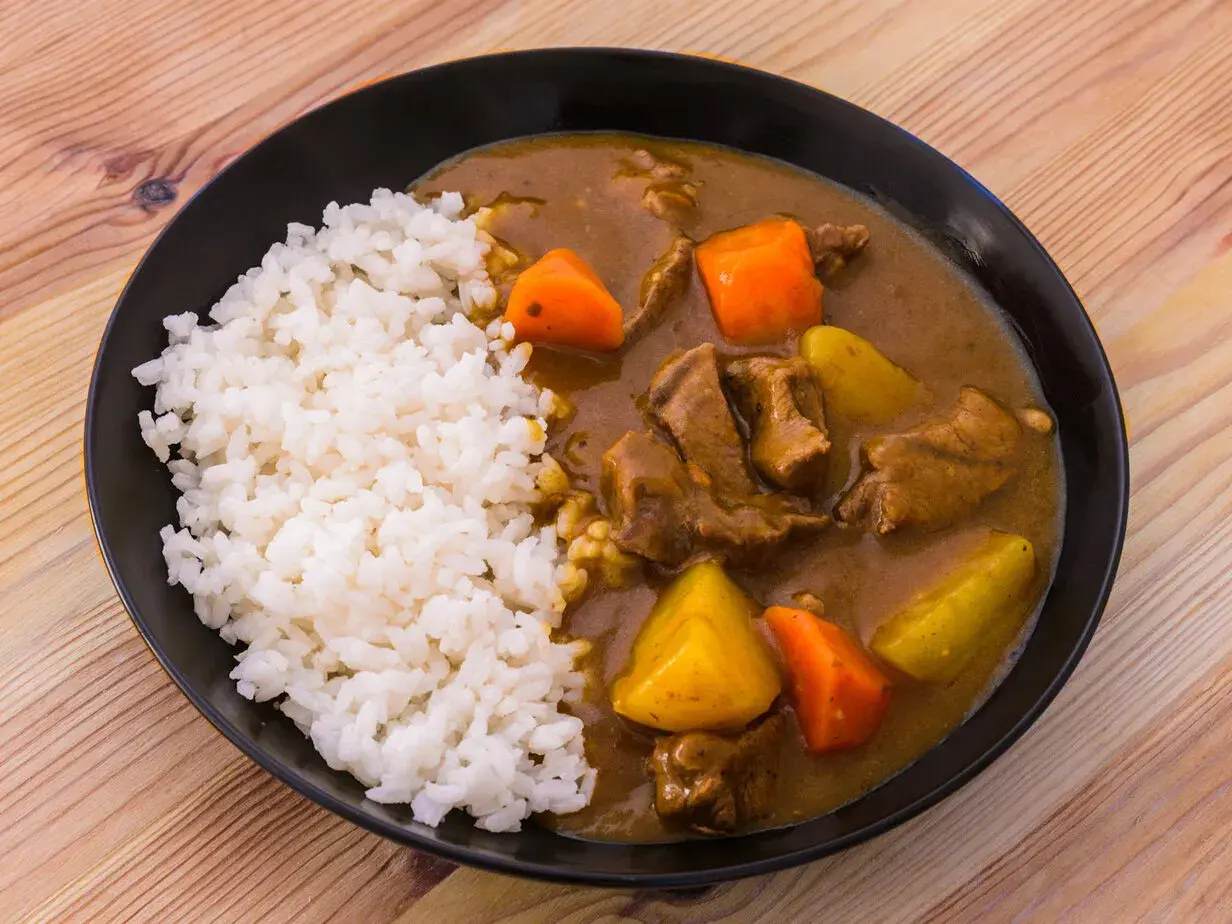 En tallrik med ångande ris och en mustig japansk curry med mört kött, potatis och morötter.