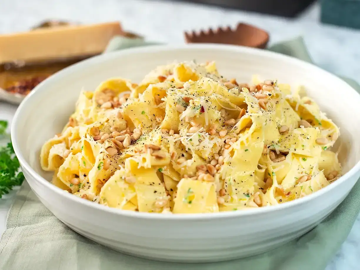 En skål med krämig pasta limone, toppad med pinjenötter och riven parmesan. Perfekt för en snabb och smakrik middag.