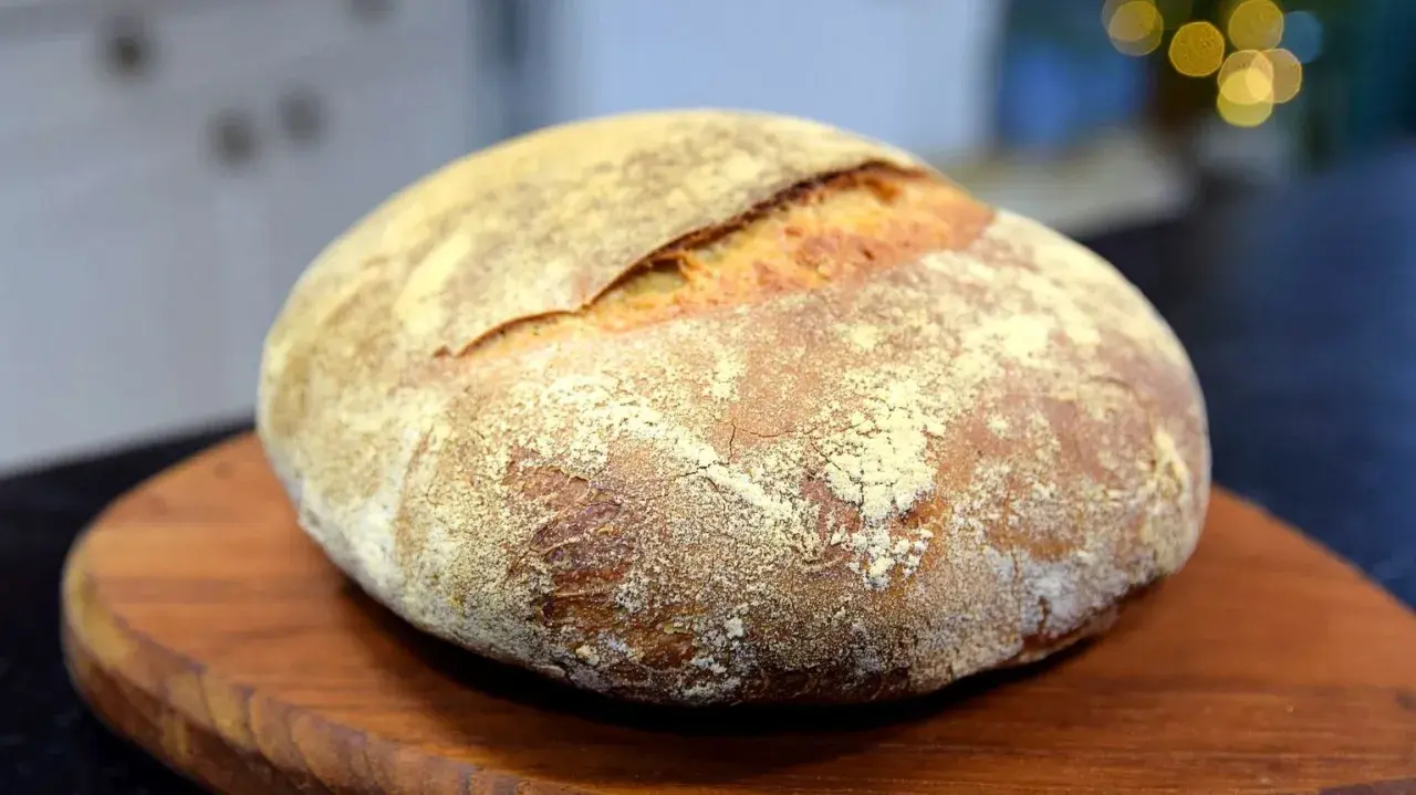 En vackert bakad surdegslimpa, perfekt för ditt surdegslimpa recept. Den gyllene skorpan och mjöliga ytan inbjuder till en smakrik upplevelse.