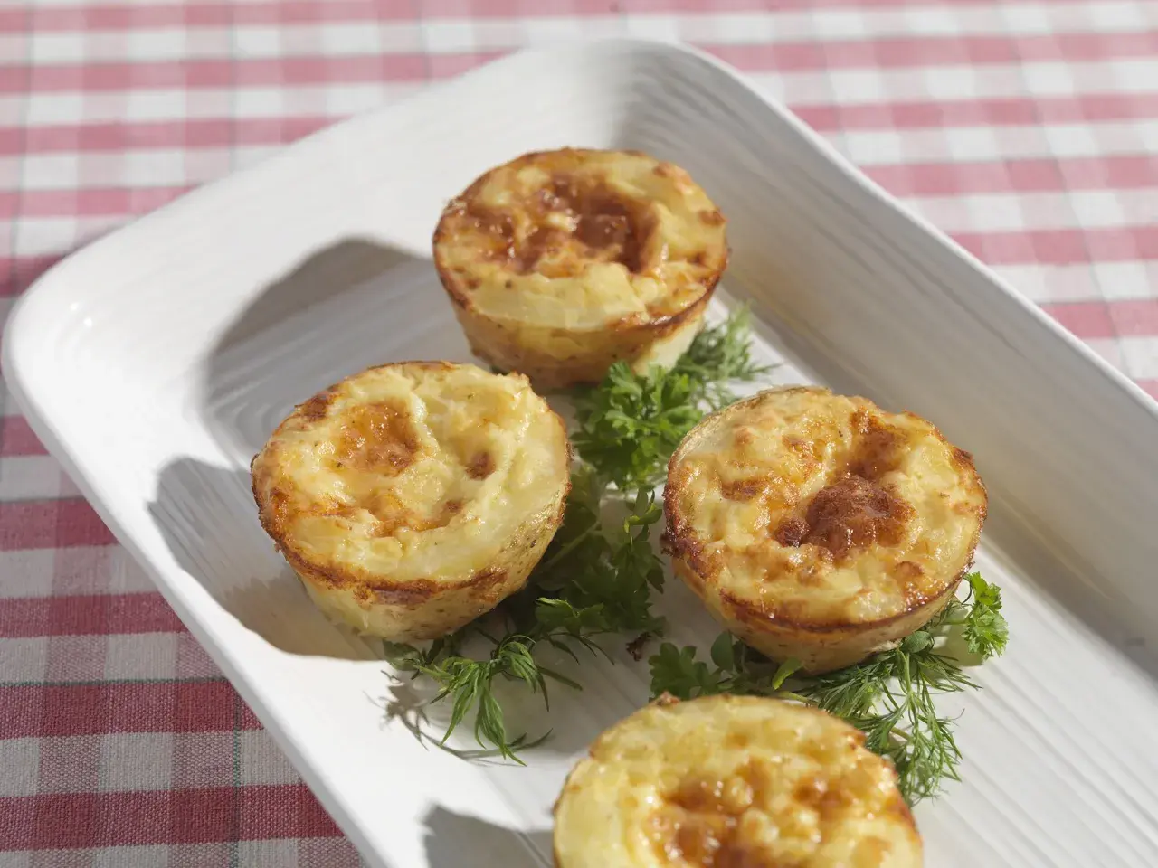 Små, gyllene potatis i muffinsform, dekorerade med färska örter. Perfekt som tillbehör eller en lätt måltid.