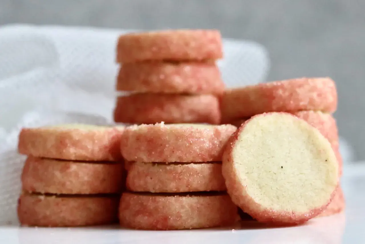 Små, runda kex med rosa socker runt kanterna, staplade på varandra. Perfekt för ett enkelt brysselkex recept.