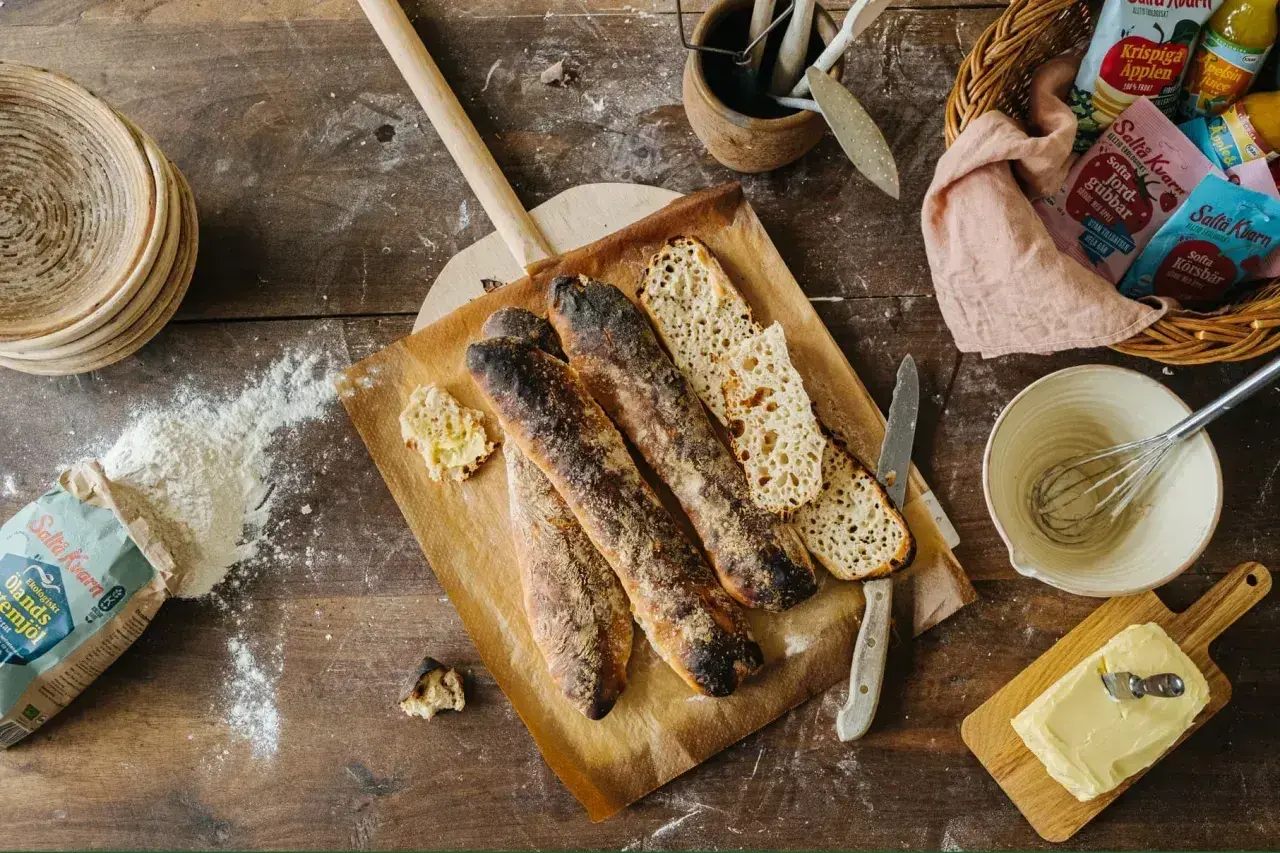 Nybakade surdegsbaguetter på en bakspade, med mjöl och smör redo för ett gott surdeg recept.
